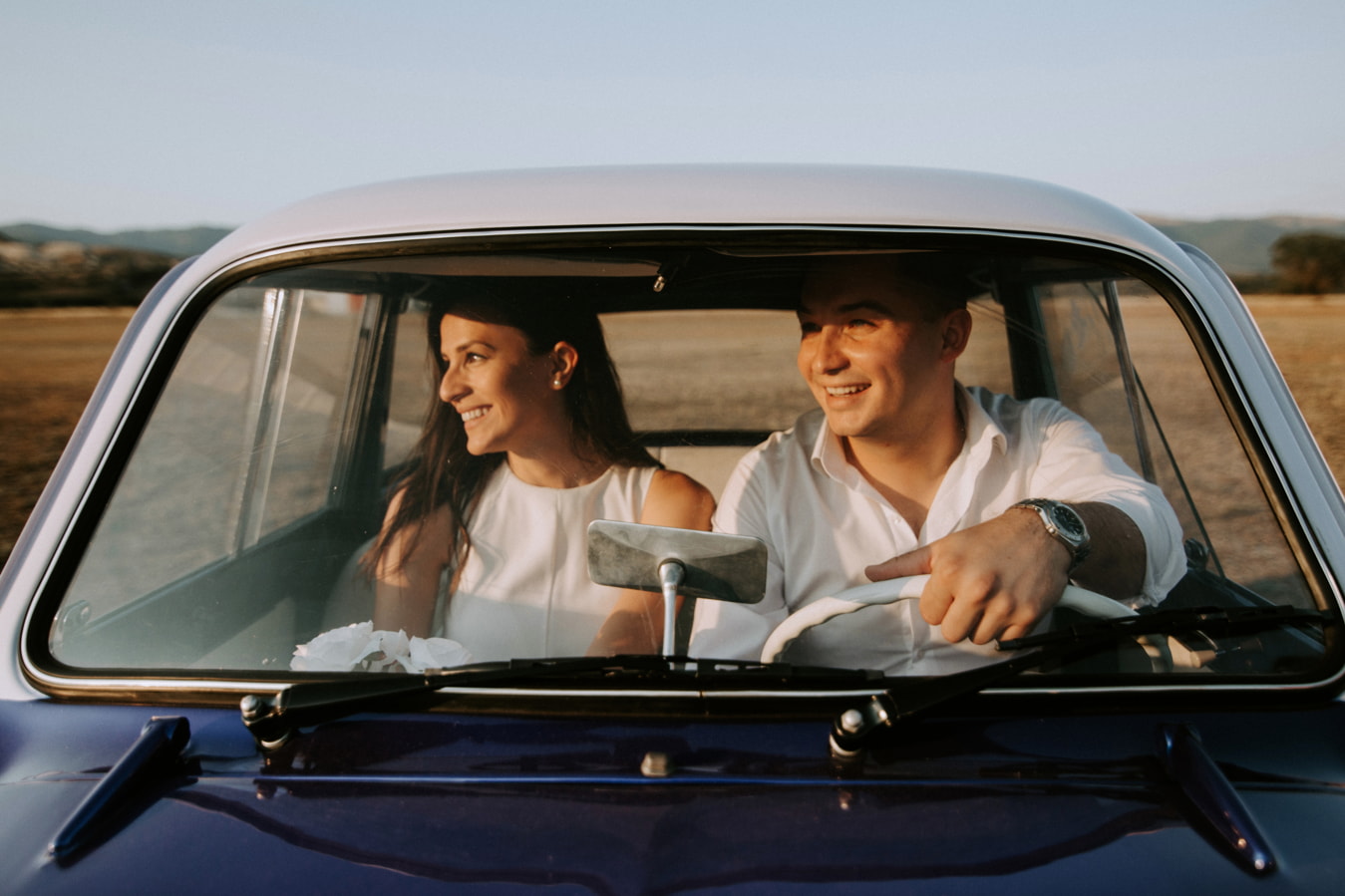 wedding couple posing into their car
